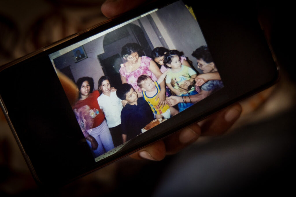 Laura Ipanaqué, madre de Carlos Javier Vega, sostiene un celular donde muestra una fotografía familiar, en el centro ella sostiene a Carlos Javier, de pequeño era rubio. 29 de abril de 2024, Guayaquil, Ecuador. Fotografía: Karen Toro